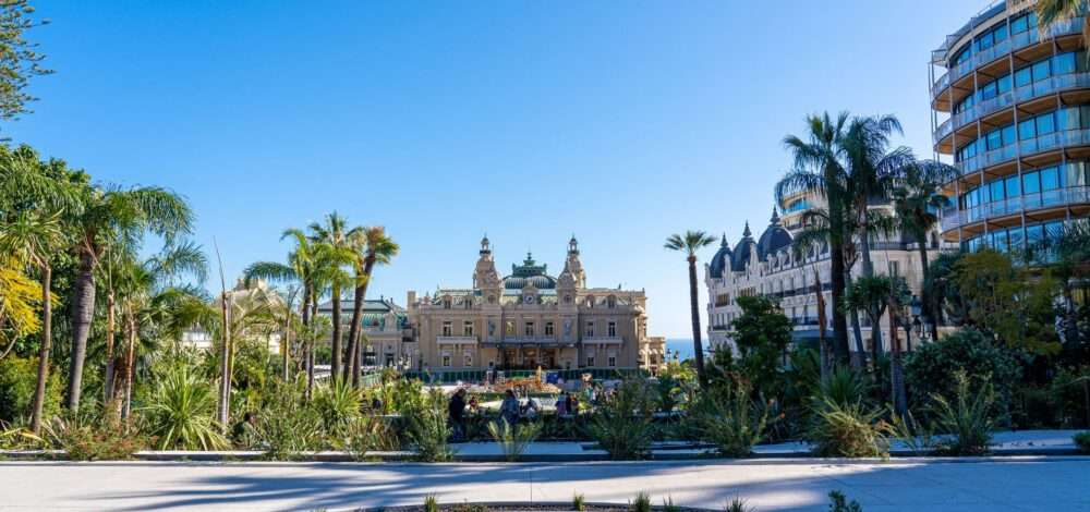 A view of the Monte Carlo Casino in Monaco with luxury cars parked in front.